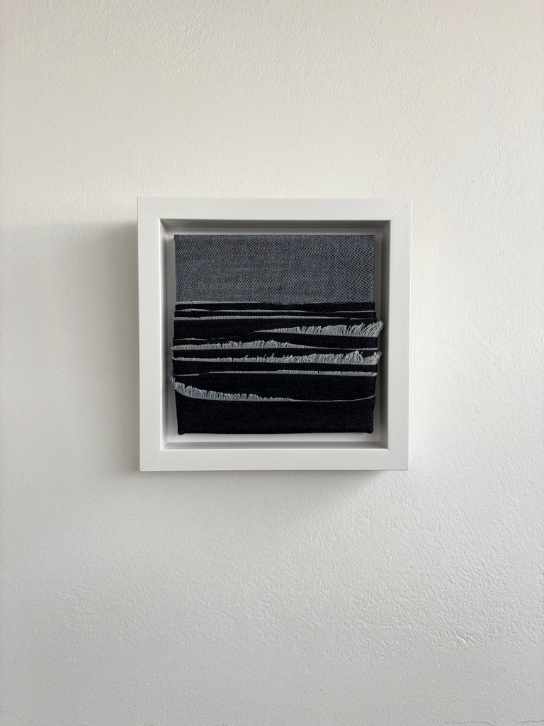 Framed abstract artwork upcycled denim sustainable art oceanscape on a white wall