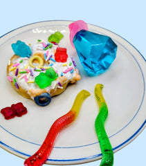 Ceramic art original sculpture. Colorful gummy worms and a dessert on a plate with a blue background