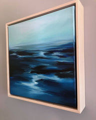 Framed oceanscape artwork with blue and black tones on a gray wall