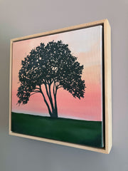 Framed artwork of a tree with a pink sky and green field. Wood floater frame, contemporary art emerging artist.