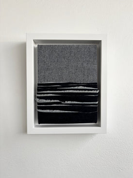 Framed abstract oceanscape made with denim on a white wall