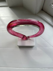 Pink looping glass sculpture on a white background