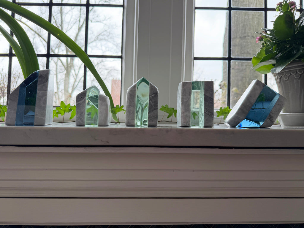 Decorative sculptures on a windowsill with plants in the background
