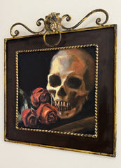 Painting of a skull with roses in a decorative gold frame.