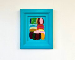 Colorful abstract art original painting by Shiri Phillips in a blue frame on a white wall