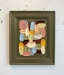 Framed abstract artwork with colorful geometric shapes on a white wall.