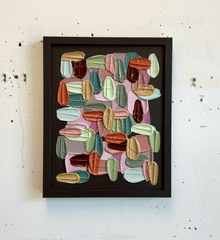 Framed textured abstract art with colorful geometric shapes on a white wall.