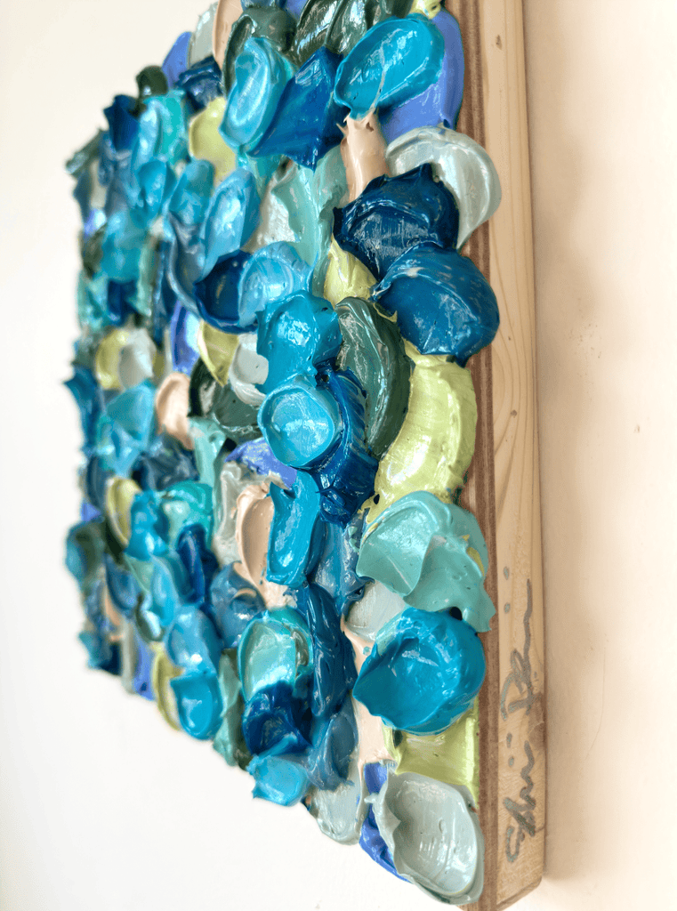Decorative wall art made from blue and green thick acrylic paint brushstrokes on a wooden panel