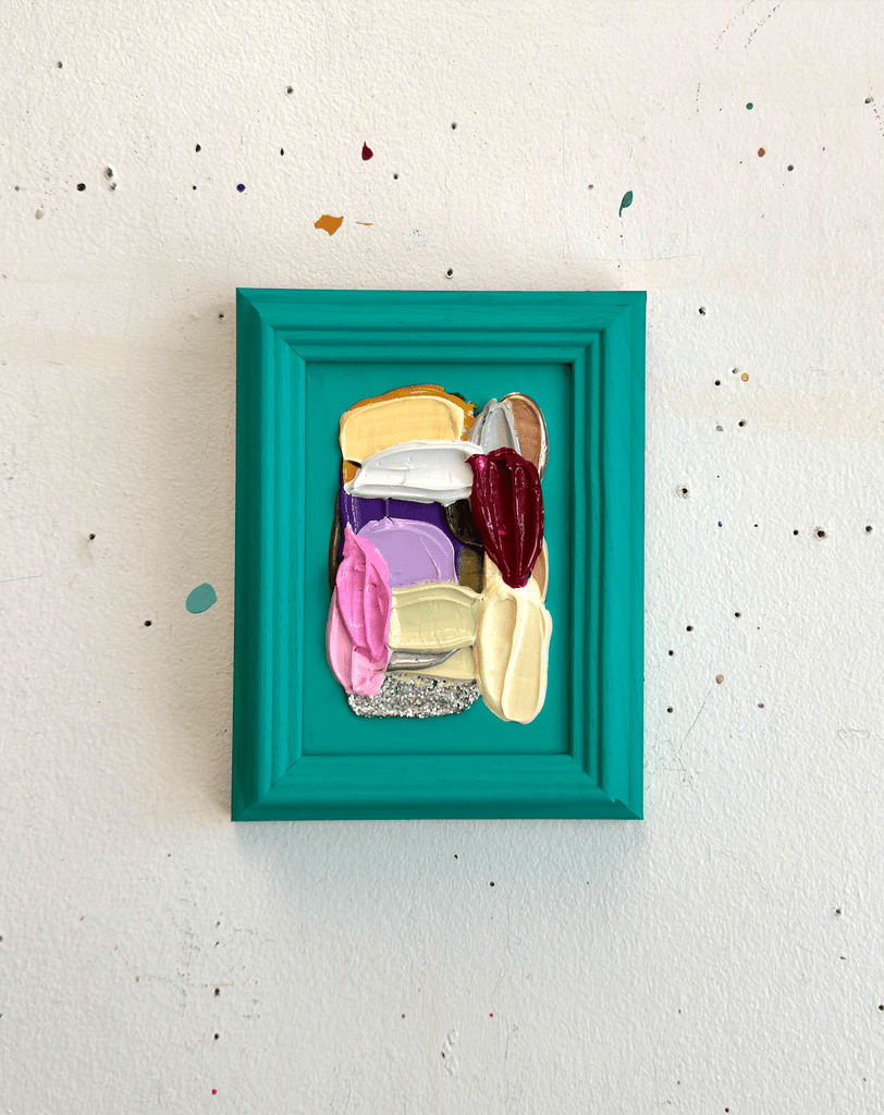 Colorful abstract art piece in a teal frame on a white wall.