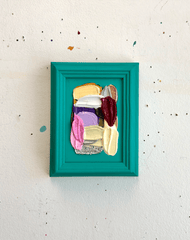 Colorful abstract art piece in a teal frame on a white wall.