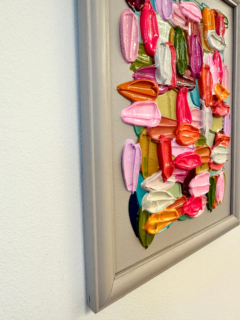 Colorful 3D abstract wall art in a frame against a white wall.