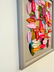Colorful 3D abstract wall art in a frame against a white wall.