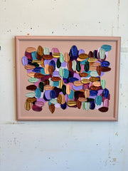 Framed abstract art with multicolored brushstrokes on a textured white wall