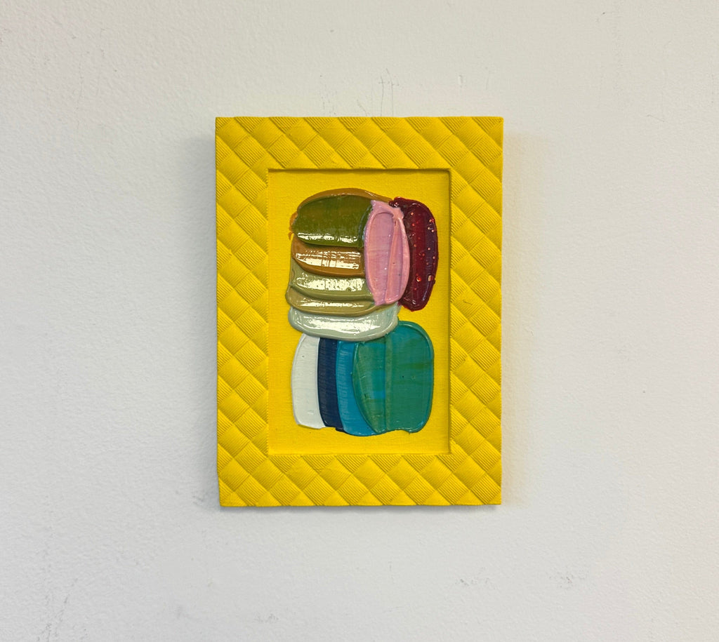 Colorful abstract art in a yellow frame hung on a wall
