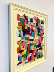 Framed abstract art original painting with colorful geometric shapes on a white wall.