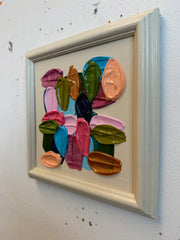 Framed abstract artwork with colorful shapes on a textured wall.
