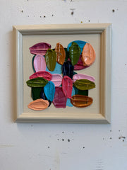Framed abstract artwork with colorful brushstrokes on a white wall
