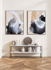Two abstract art paintings on canvas on a wall above a console table with decor items.