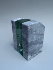 Marble-like sculpture with green and gray patterns on a light gray background