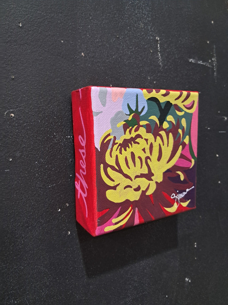 Small square canvas painting with colorful floral design against a black background